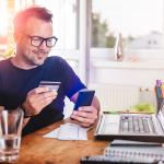 Man in his home office using a credit card for an online transaction.