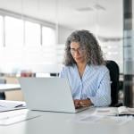 Middle-aged businesswoman busy working on tasks in her laptop in an office.