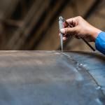 NDT inspector using welding gauge to inspect joint preparation or groove weld on a structure.
