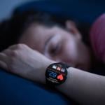 Person wearing sleep tracking heart rate monitor smartwatch in bed.