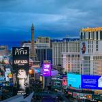 The Strip skyline in Las Vegas with advertising billboards including Lady Gaga, neon lights on iconic hotels and casinos after sunset.