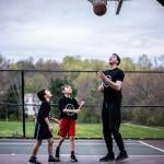 A private sports coach in a basketball session with two young boys.
