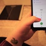 A woman with a tattoo dials the national suicide hotline '988' number from the floor in front of a body weight scale. 