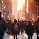A crowd of people walking in a city street during sunset.
