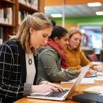 A female marketing professional composes email in her laptop in an office library.