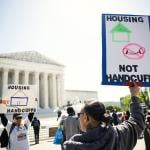 Homeless rights activists hold up signs saying "Housing, Not Handcuffs" outside of the U.S. Supreme Court on April 22, 2024 in Washington, DC.