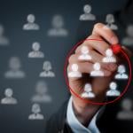 A hand encircling a group of business people graphic figures with a red marker.