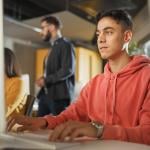 A male student using a desktop computer for application tasks.
