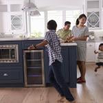 Parents prepare food as their children play around the kitchen.