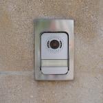 A surveillance video doorbell on a modern house's door.