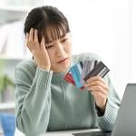 A woman looking worried at her four credit cards.