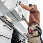 A cabinetmaker finishing a white, modern cabinet installation