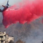 A firefighting aircraft drops the fire retardant Phos-Chek near homes during the Palisades Fire on January 10, 2025 in Topanga, California.