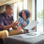 A young couple discussing finances while holding paperwork.