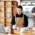 A cafe small business owner calculating costs of products.