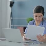 A female nurse reading documents in an office.