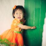 A young girl wearing an orange Halloween dress crying during a party.