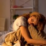 A tired woman sitting on her bed.