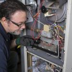 A technician inspects a gas furnace before its cleaning.