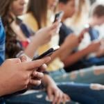A row of high school students using mobile phones.