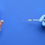 A hand refusing to receive a vaccine syringe.