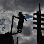 Silhouette of one of the children standing on the edge of an abandoned wooden fort.