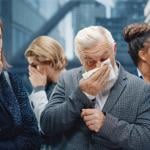 A middle-aged man sneezes in a crowded elevator.