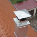 Aerial view of metal pipe chimney with cap on a Spanish tile roof.                          