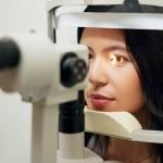 A woman in front of a slit lamp as an eye specialist takes her vision test.