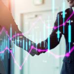 Stock chart graphics over business people shaking hands.