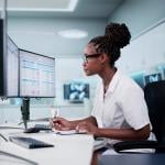 A hospital staff looking at spreadsheets and billing codes using desktop with multiple monitors.