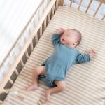 An infant quietly sleeps in a crib.