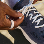 Close up on a navy athletic shoe's strings being tied up.