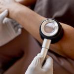 A doctor holds a dermatoscope over a patient's skin to examine for skin cancer.