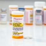 A generic prescription medicine pill bottle in front of a row of other pill bottles.