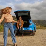 A couple enjoying their trip behind a blue 2023 Ford Mustang Mach-E GT.