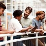 An office team engaged in discussion while standing by a railing.