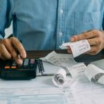 A man computes bills using a calculator.