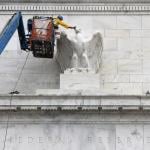 Workers paint an eagle statue on the Marriner S. Eccles Federal Reserve Board Building in Washington, DC.
