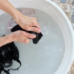 A couple of bras being hand-washed in a white basin.