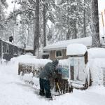 Mobile home owners shovel snow during a winter storm on March 02, 2024 in the Sierra Nevada mountains in Truckee, California.