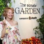 Pamela Anderson poses holding up a lip produce in front of "Sonsie Garden" with Shopify on October 24, 2025 in New York City.