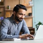 A happy business man working with a laptop in his home office.