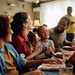 A big family laughing during Thanksgiving dinner at home.