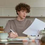 A young man reviewing a document during breakfast.