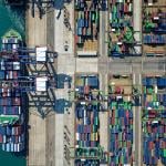 Aerial view on ships, cranes, and cargo containers by the quayside of a dock.