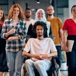 A diverse group of young business people, with a person in wheelchair at the center, showcasing community and accessibility.