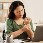 A female employee working from home having wrist aches.