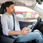 A male driver in shock as he is texting while driving.