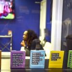 Jon'Aric Nathaniel waits from his clinical appointment at Open Arms Healthcare Center behind a window lined by pamphlets in the foreground on HIV.